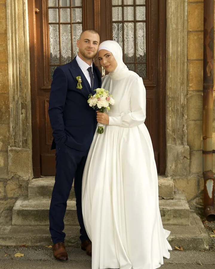 A bride and groom standing together on the steps of an old building with tall wooden doors.
